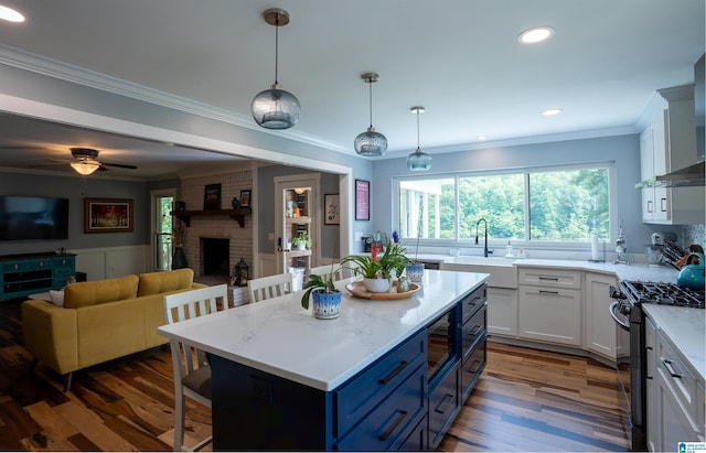 7835 Windsong Dr, Trussville, AL 35173 - kitchen featuring gas range, a kitchen bar, open floor plan, blue cabinets, and dark wood-style flooring