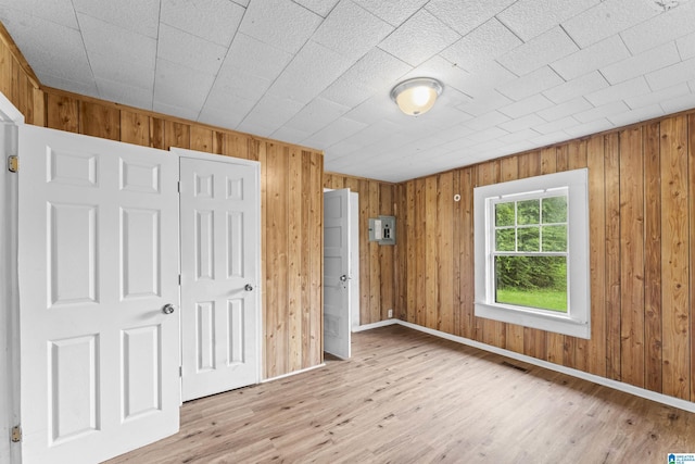 606 W Pine St, Sylacauga, AL 35150 - unfurnished bedroom with light wood-style flooring, a closet, and wood walls