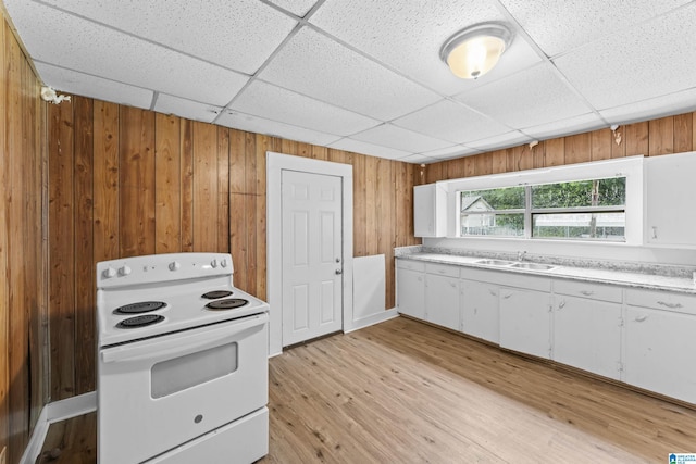 606 W Pine St, Sylacauga, AL 35150 - kitchen with white electric stove, a drop ceiling, wooden walls, white cabinetry, and light countertops
