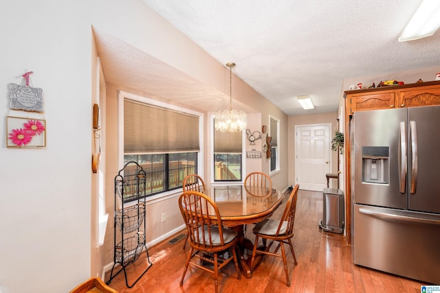 20571 Faynell Cir, Woodstock, AL 35188 - dining room with light wood-style floors, a chandelier, and a textured ceiling