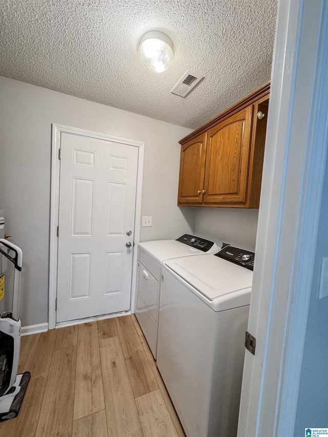 489 Bailey Loop Rd, Gardendale, AL 35071 - laundry room with independent washer and dryer, cabinet space, light wood-style flooring, a textured ceiling, and water heater