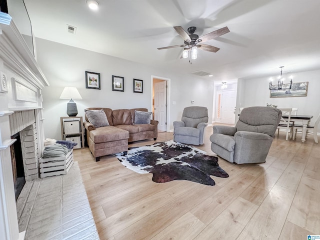 489 Bailey Loop Rd, Gardendale, AL 35071 - living area with light wood-type flooring, a brick fireplace, a ceiling fan, and a chandelier