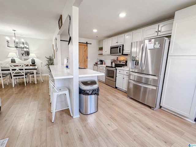 489 Bailey Loop Rd, Gardendale, AL 35071 - kitchen with appliances with stainless steel finishes, a barn door, a kitchen bar, a peninsula, and white cabinets