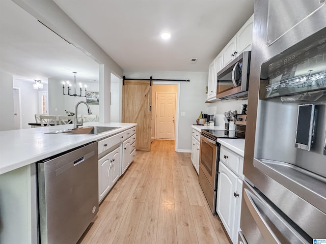 489 Bailey Loop Rd, Gardendale, AL 35071 - kitchen featuring stainless steel appliances, a barn door, white cabinetry, light wood finished floors, and light countertops