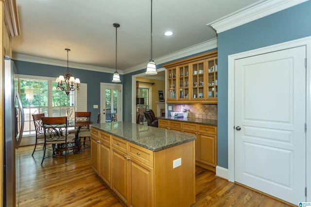 5668 Carrington Lake Pkwy, Trussville, AL 35173 - kitchen featuring freestanding refrigerator, wood finished floors, glass insert cabinets, tasteful backsplash, and hanging light fixtures