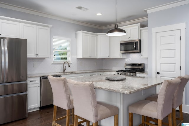 7593 Paine Dr, Trussville, AL 35173 - kitchen featuring stainless steel appliances, a kitchen bar, ornamental molding, white cabinets, and decorative backsplash