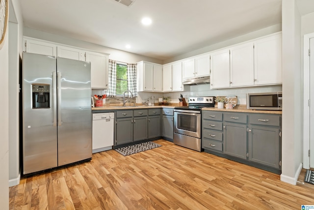 405 Willow Dr, Hueytown, AL 35023 - kitchen featuring appliances with stainless steel finishes, gray cabinets, under cabinet range hood, white cabinetry, and light wood-style flooring