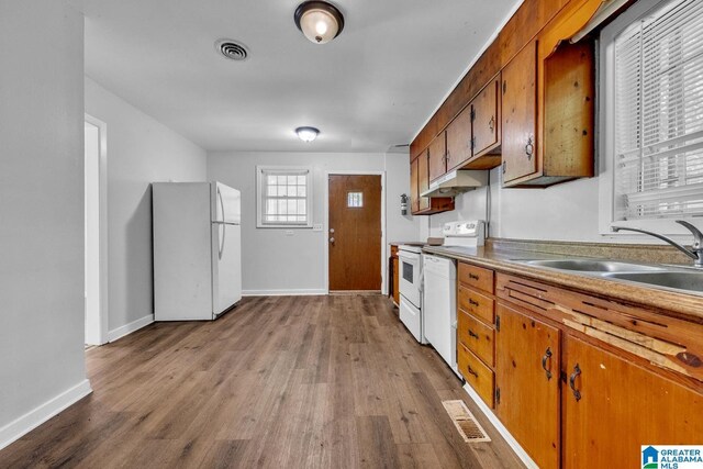 1341 Hatfield Ln, Birmingham, AL 35215 - kitchen with white appliances, wood finished floors, brown cabinets, and under cabinet range hood