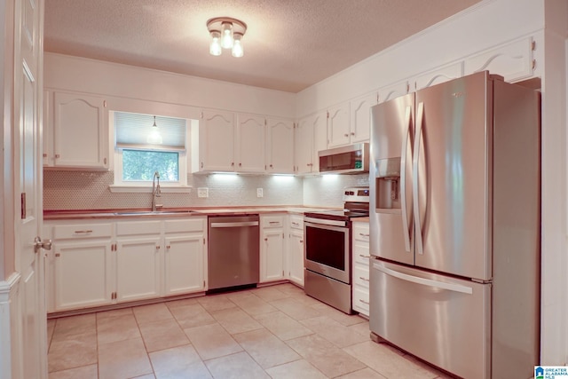 204 Shalimar Cir, Alabaster, AL 35007 - kitchen featuring appliances with stainless steel finishes, tasteful backsplash, white cabinets, a textured ceiling, and light tile patterned floors