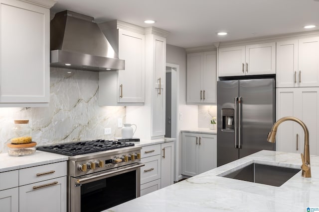 3709 Dover Dr, Mountain Brook, AL 35223 - kitchen with wall chimney exhaust hood, stainless steel appliances, backsplash, white cabinetry, and recessed lighting