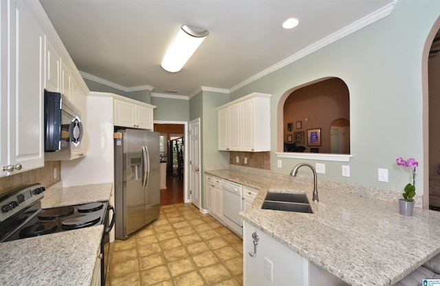 401 Waterford Highlands Way, Calera, AL 35040 - kitchen featuring appliances with stainless steel finishes, arched walkways, tasteful backsplash, a peninsula, and ornamental molding