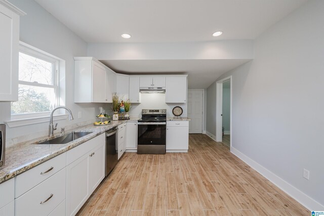 1330 14th Ave N, Bessemer, AL 35020 - kitchen featuring appliances with stainless steel finishes, under cabinet range hood, light wood finished floors, white cabinets, and light stone countertops