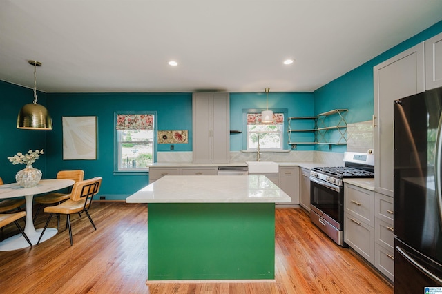 5100 7th Ct S, Birmingham, AL 35212 - kitchen featuring freestanding refrigerator, stainless steel range with gas cooktop, open shelves, a kitchen island, and light wood-style flooring