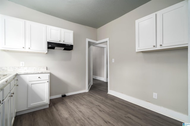 2129 Pike Rd, Birmingham, AL 35218 - kitchen with dark wood-type flooring, white cabinetry, under cabinet range hood, and light countertops