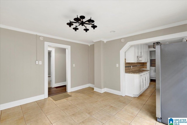 1125 SW 15th St, Birmingham, AL 35211 - kitchen featuring freestanding refrigerator, white cabinetry, backsplash, ornamental molding, and light tile patterned floors