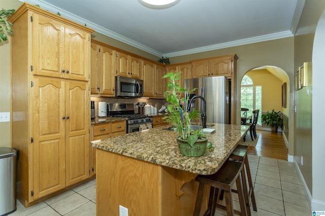 8587 Hayes Rd, Helena, AL 35022 - kitchen featuring stainless steel appliances, light tile patterned floors, arched walkways, stone counters, and crown molding