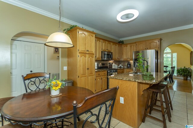 8587 Hayes Rd, Helena, AL 35022 - kitchen featuring appliances with stainless steel finishes, arched walkways, ornamental molding, light tile patterned flooring, and a center island with sink