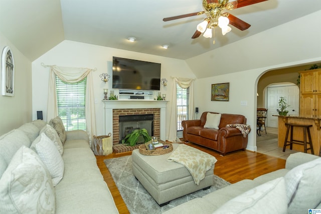 8587 Hayes Rd, Helena, AL 35022 - living area with arched walkways, vaulted ceiling, a ceiling fan, light wood-type flooring, and a brick fireplace