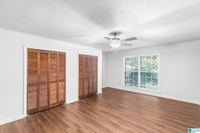 2005 Crossvine Rd, Hoover, AL 35244 - unfurnished bedroom featuring multiple closets, wood finished floors, a textured ceiling, and ceiling fan