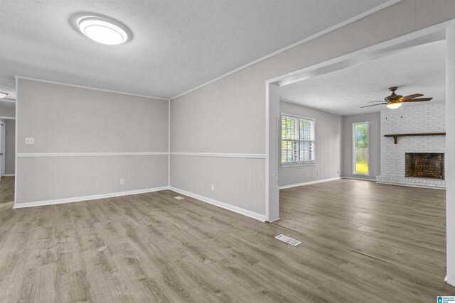 4 Carriage Rd, Anniston, AL 36206 - unfurnished living room featuring wood finished floors, ceiling fan, a brick fireplace, and a textured ceiling