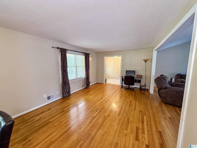 1027 Creek Trl, Anniston, AL 36206 - living room featuring light wood-style flooring, an office area, and a textured ceiling
