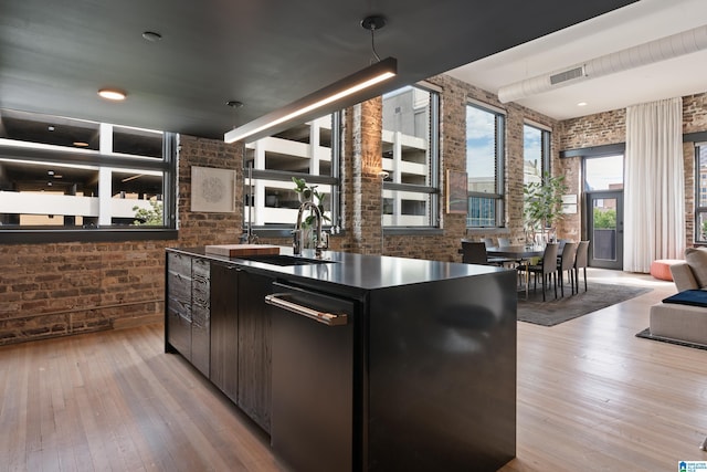 1801 2nd Ave N Unit 415, Birmingham, AL 35203 - kitchen with brick wall, light wood finished floors, stainless steel dishwasher, dark countertops, and a towering ceiling
