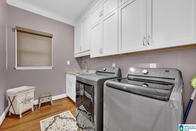 5557 Lakes Edge Dr, Hoover, AL 35242 - laundry room featuring washing machine and clothes dryer, light wood-style floors, cabinet space, and crown molding