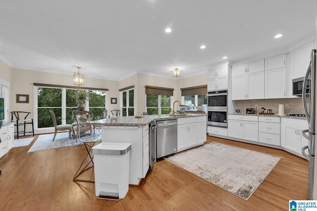 5557 Lakes Edge Dr, Hoover, AL 35242 - kitchen with stainless steel appliances, crown molding, an island with sink, a chandelier, and white cabinets