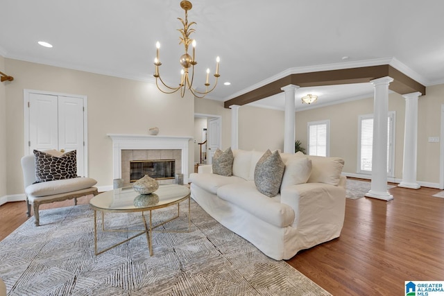 5557 Lakes Edge Dr, Hoover, AL 35242 - living room featuring decorative columns, wood finished floors, ornamental molding, a tiled fireplace, and recessed lighting