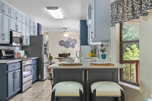 505 Waterside Cir, Mccalla, AL 35111 - kitchen featuring stainless steel appliances, decorative backsplash, light countertops, ceiling fan, and a textured ceiling