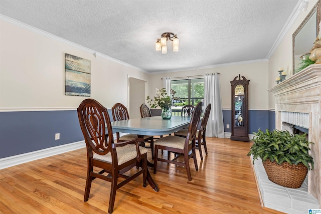 505 Waterside Cir, Mccalla, AL 35111 - dining space with a textured ceiling, light wood-type flooring, crown molding, and a brick fireplace