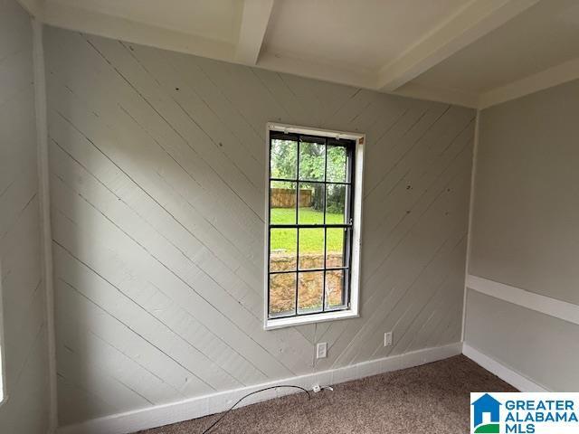 1511 43rd St, Birmingham, AL 35208 - empty room featuring beam ceiling, carpet, and wood walls