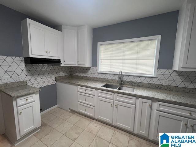 2732 29th St, Birmingham, AL 35208 - kitchen with white cabinets, backsplash, under cabinet range hood, and light tile patterned floors