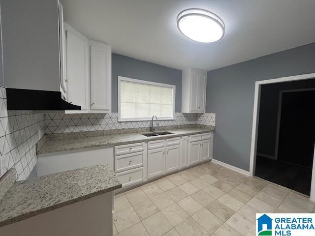 2732 29th St, Birmingham, AL 35208 - kitchen with tasteful backsplash, light stone counters, and white cabinetry