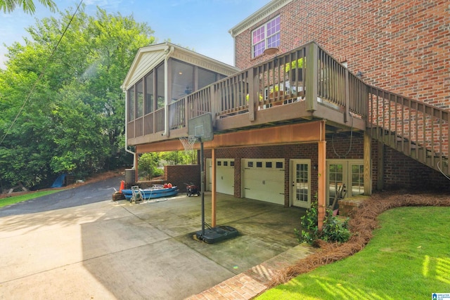 1528 Wellington Rd, Homewood, AL 35209 - rear view of property featuring an attached garage, a sunroom, driveway, brick siding, and a deck