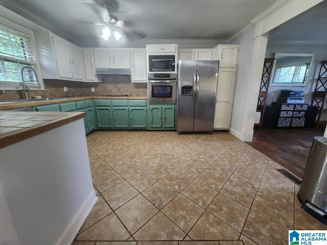 2030 Carraway St, Birmingham, AL 35235 - kitchen with stainless steel appliances, crown molding, green cabinets, light tile patterned flooring, and ceiling fan