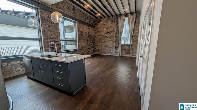 1801 2nd Ave N Unit 406, Birmingham, AL 35203 - kitchen featuring stainless steel dishwasher, an island with sink, dark wood finished floors, brick wall, and gray cabinets