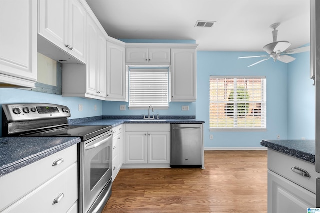 147 Old Brook Pl, Birmingham, AL 35242 - kitchen featuring appliances with stainless steel finishes, dark countertops, a ceiling fan, light wood-style flooring, and white cabinetry
