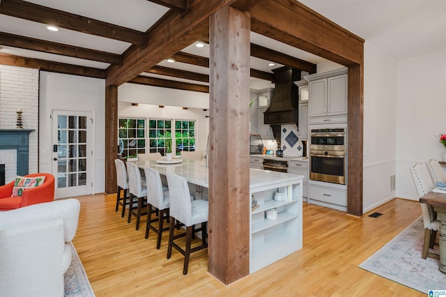 3204 Woodford Way, Birmingham, AL 35242 - kitchen featuring stainless steel double oven, light wood-style flooring, beam ceiling, custom range hood, and a kitchen breakfast bar