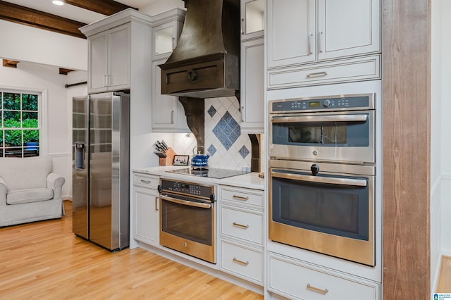 3204 Woodford Way, Birmingham, AL 35242 - kitchen featuring appliances with stainless steel finishes, premium range hood, decorative backsplash, light wood-style flooring, and glass insert cabinets