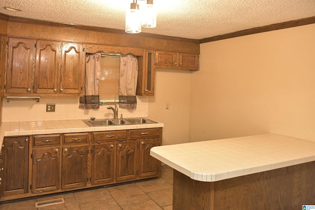 201 61st St, Fairfield, AL 35064 - kitchen featuring ornamental molding, tile countertops, a textured ceiling, backsplash, and a peninsula