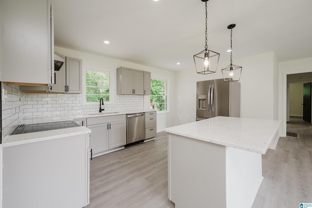201 Sun Valley Rd, Center Point, AL 35215 - kitchen featuring stainless steel appliances, a center island, decorative backsplash, light wood-type flooring, and light stone counters
