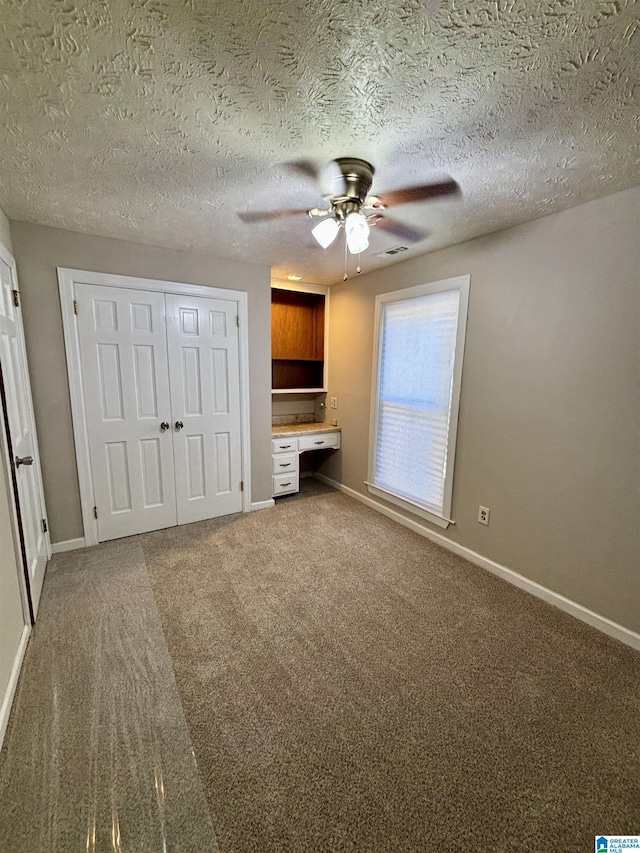 1221 Dalraida Rd, Montgomery, AL 36109 - unfurnished living room featuring built in desk, a ceiling fan, carpet, and a textured ceiling