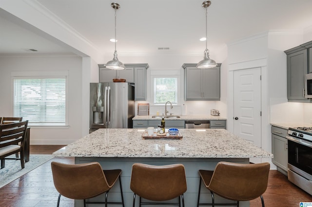 1268 Shades Ter, Irondale, AL 35210 - kitchen with appliances with stainless steel finishes, gray cabinetry, a breakfast bar, a kitchen island, and ornamental molding