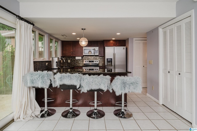 3655 Haven View Cir, Hoover, AL 35216 - kitchen with appliances with stainless steel finishes, a peninsula, decorative backsplash, a breakfast bar, and dark brown cabinets