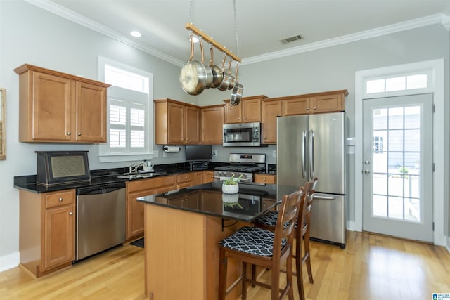 4650 Nicholas Dr, Bessemer, AL 35022 - kitchen featuring appliances with stainless steel finishes, crown molding, light wood finished floors, a kitchen bar, and a center island