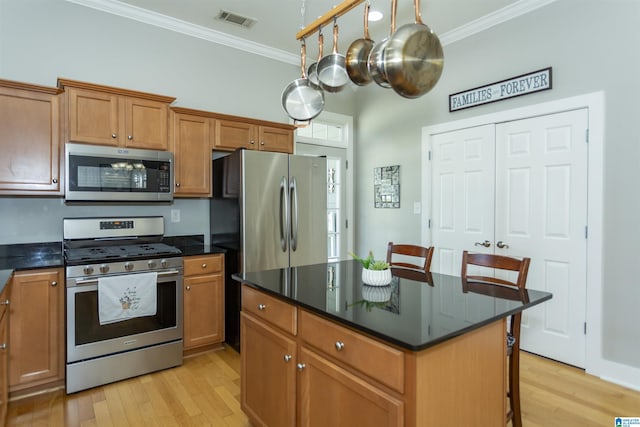 4650 Nicholas Dr, Bessemer, AL 35022 - kitchen featuring appliances with stainless steel finishes, ornamental molding, light wood-style floors, a breakfast bar area, and brown cabinetry