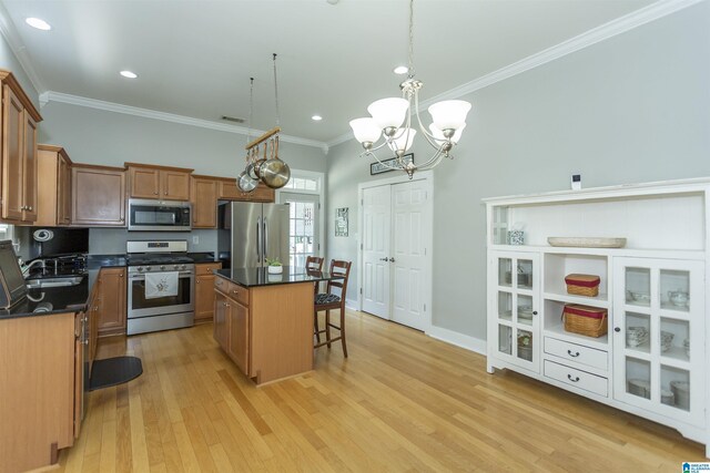 4650 Nicholas Dr, Bessemer, AL 35022 - kitchen with appliances with stainless steel finishes, a kitchen island, dark countertops, light wood finished floors, and a breakfast bar