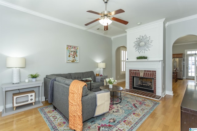 4650 Nicholas Dr, Bessemer, AL 35022 - living area with arched walkways, ornamental molding, ceiling fan, light wood finished floors, and a brick fireplace