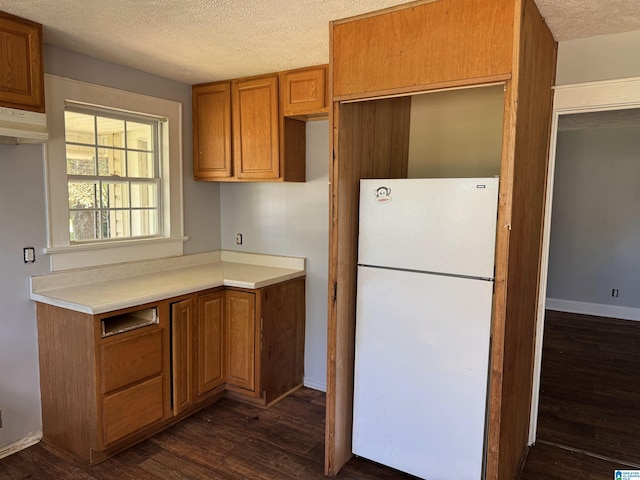 319 Lapsley Ave, Anniston, AL 36207 - kitchen featuring freestanding refrigerator, dark wood-style floors, a textured ceiling, brown cabinetry, and light countertops
